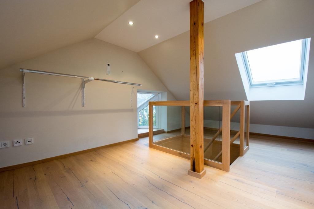 Leeres ausgebautes Dachgeschoss mit sichtbaren Holzbalken und Dachfenstern