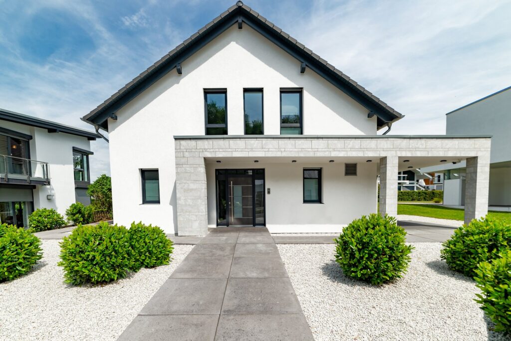 Weißes Einfamilienhaus mit Hecke, Vorgarten und Eingangsbereich