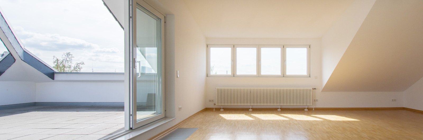 Leergeräumtes Dachzimmer mit Dachschräge und Balkontür nach dem Auszug