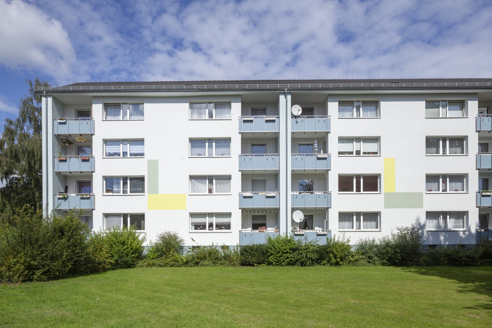 Mehrfamilienhaus aus den sechziger Jahren mit Balkonen und Rasenfläche