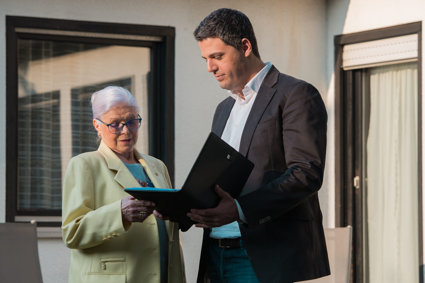 David Gold von GOLD IMMOBILIEN übergibt einer Eigentümerin Unterlagen an der Haustür