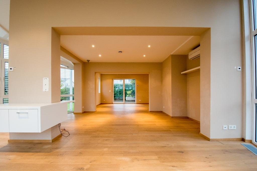 Heller, leerer Wohnraum mit Parkettboden und Blick in den Garten