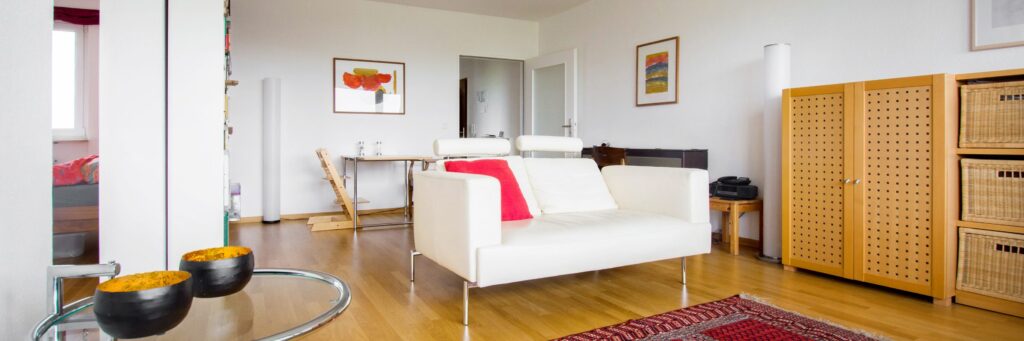 Helles Wohnzimmer mit weißem Sofa, Parkett und Sitzgruppe in einer Eigentumswohnung