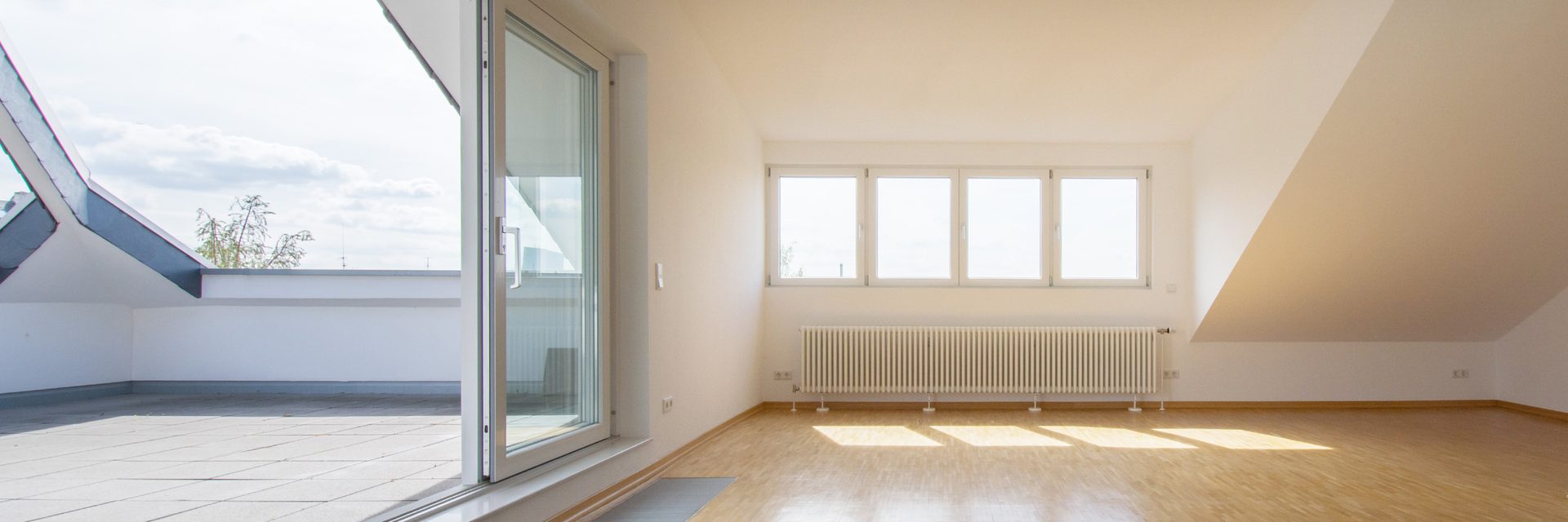 Dachgeschosszimmer mit Dachschräge, Holzboden und Fenster