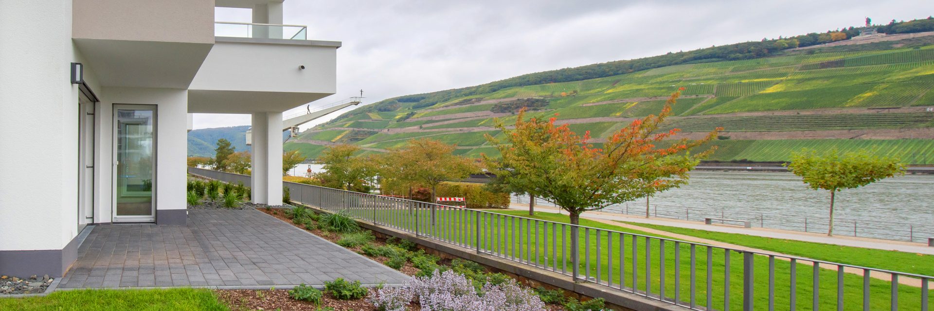 Weisses Einfamilienhaus mit Rasenfläche und Terrasse bei Sonnenschein