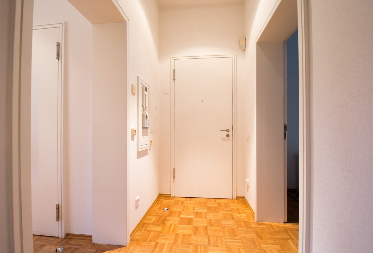 Ruhiger Hausflur mit geschlossener Wohnungstür als Sinnbild für einen diskreten Verkauf