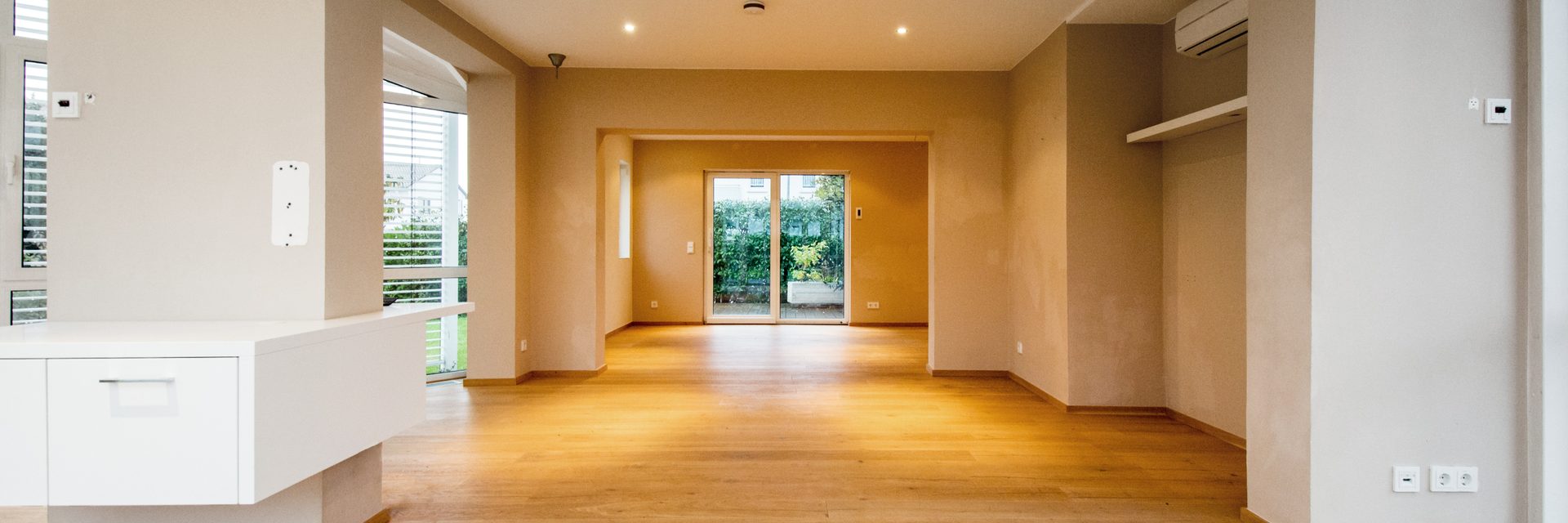 Leerer Wohnraum mit Holzboden und Blick auf die Terrassentür